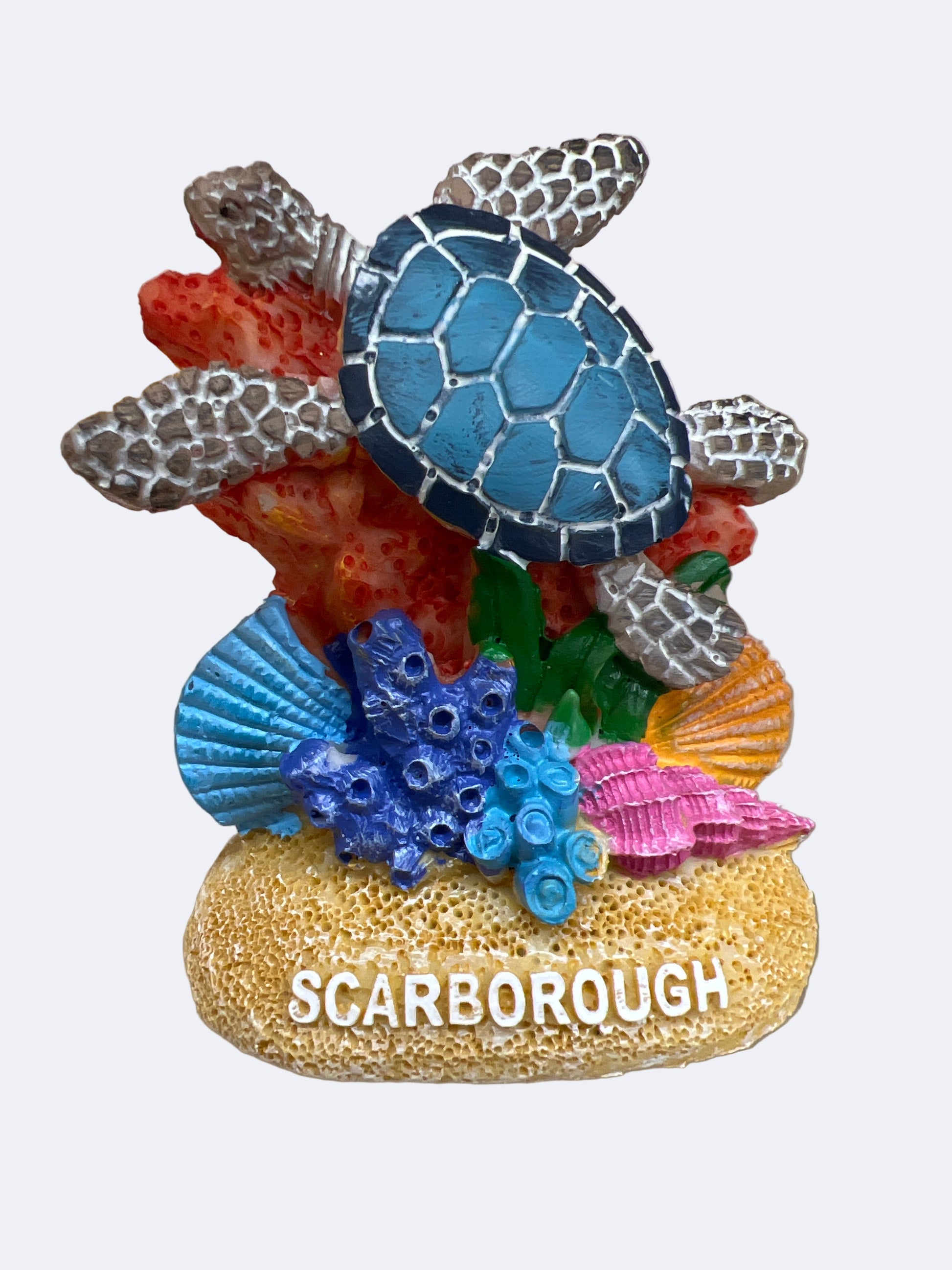 A figurine of a sea turtle with a blue back, black patterns on its shell, and surrounded by colorful coral and shells, with the text 'SCARBOROUGH' on the base.