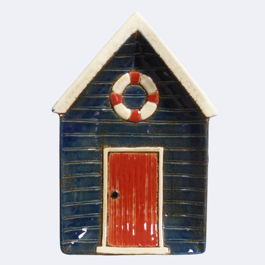 A ceramic plate shaped like a beach hut with a blue exterior, white trim, and a red door.