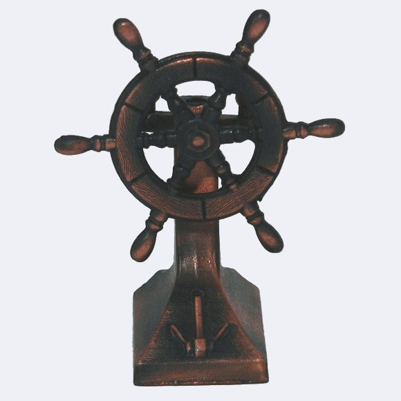 A bronze-colored metal pencil sharpener designed to resemble a ship's wheel.