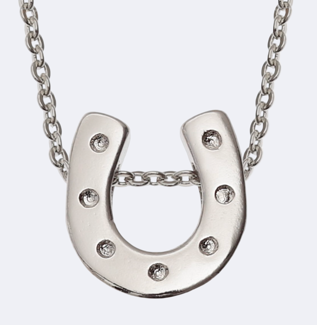 A silver-colored horseshoe-shaped pendant necklace with small inset stones, attached to a chain.