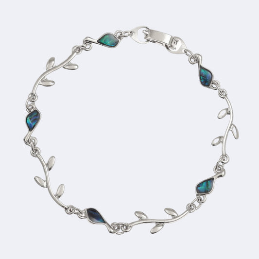 A silver-colored bracelet with blue paua shell accents, designed to resemble a bird and branch pattern.