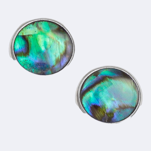 A pair of round stud earrings with paua shell inlays, set in a silver-colored frame.