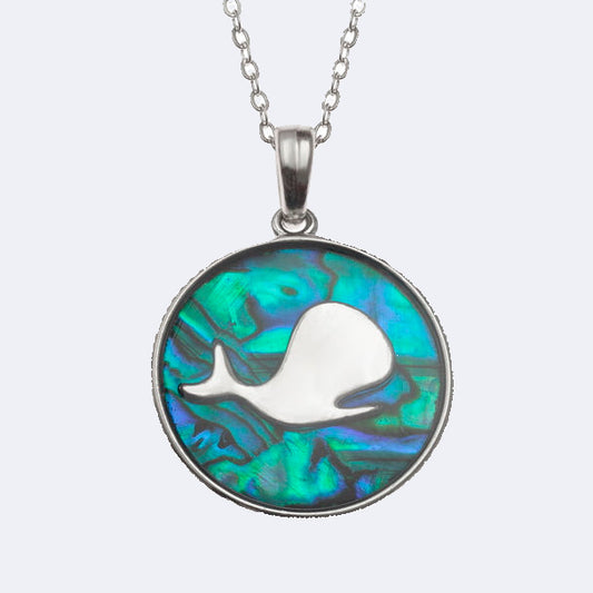 A necklace with a round blue paua shell pendant featuring a silhouette of a whale in the center, surrounded by a metallic rim.