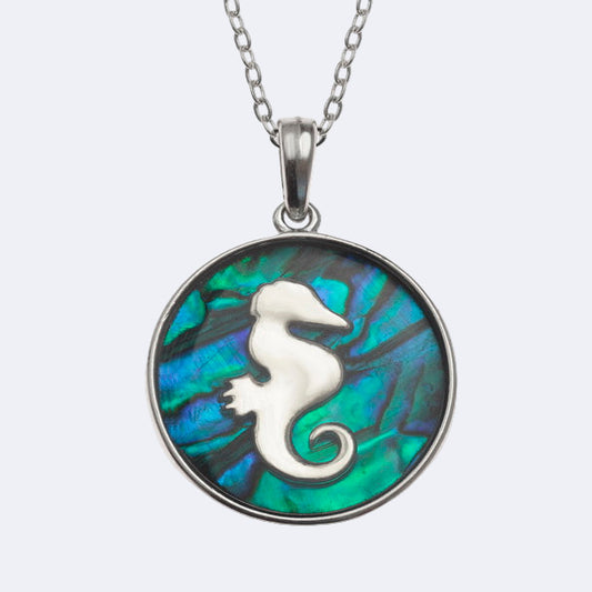 A seahorse necklace with a blue paua shell pendant and a silver metal seahorse silhouette inlay, attached to a chain.