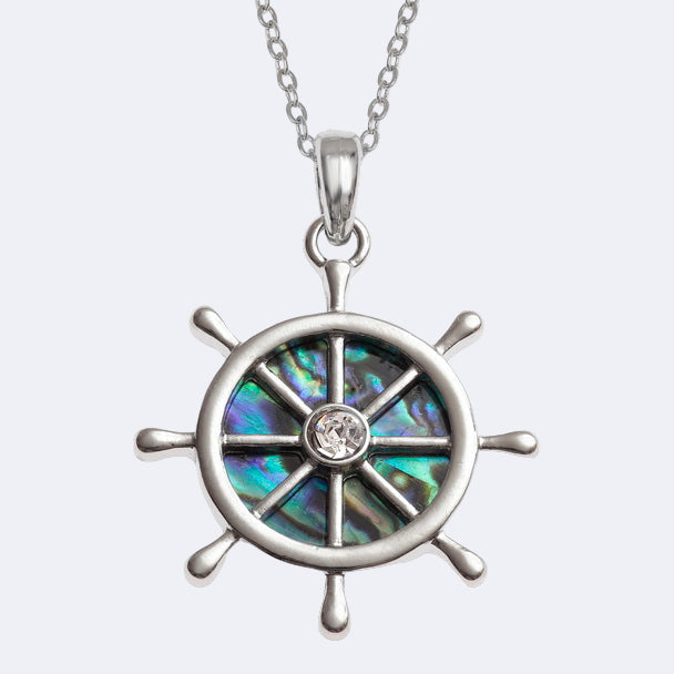 A silver-colored ship's wheel necklace pendant with a natural Paua shell and an inset glass stone in the center, attached to a chain.