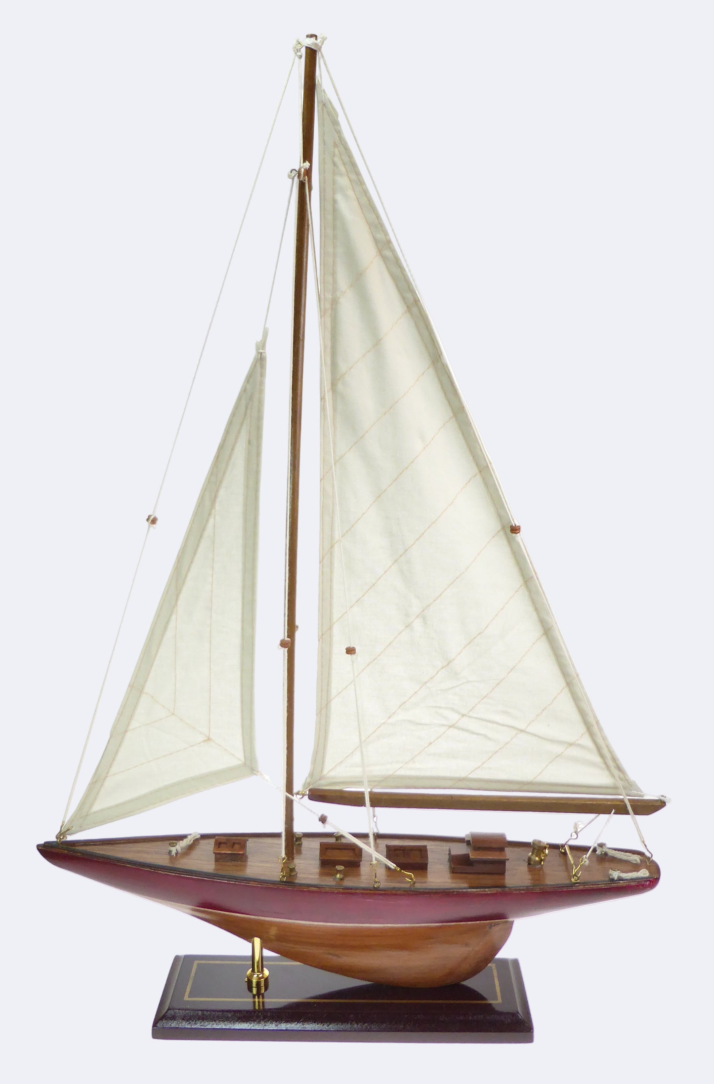 A model of a sailing yacht with fabric sails, featuring a wooden body and a display stand.