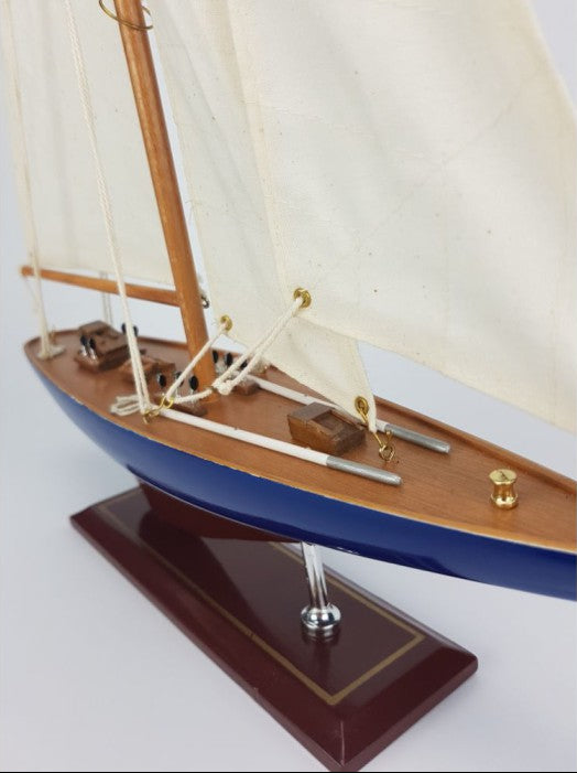 Model sailboat with wooden deck and white sails on a white background