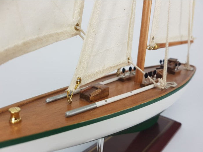 Model sailboat with wooden deck and white sails on a white background