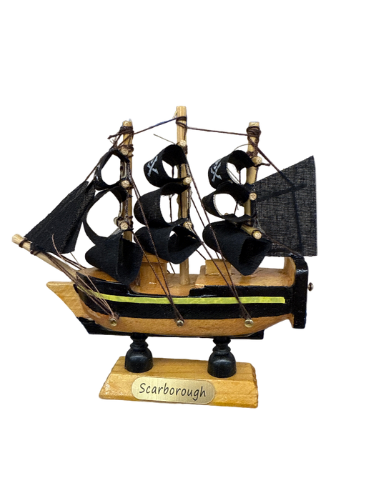 Model ship with black sails and 'Scarborough' label on a plain background