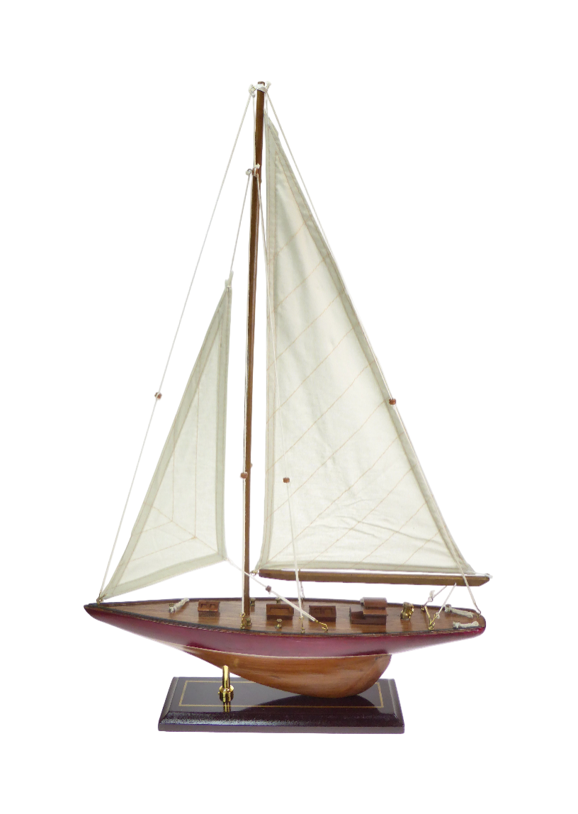 Model sailboat with white sails on a wooden base against a white background
