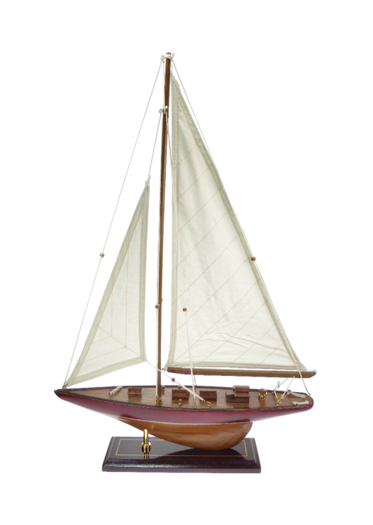 Model sailboat with white sails on a wooden base against a white background