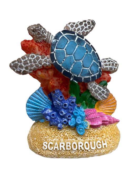 Decorative turtle figurine with coral and shells on a stand, featuring the word 'Scarborough'.