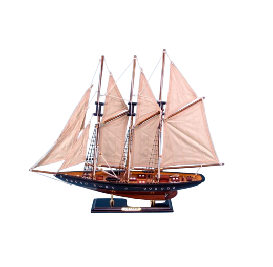 Model sailboat with three masts and white sails against a blue background