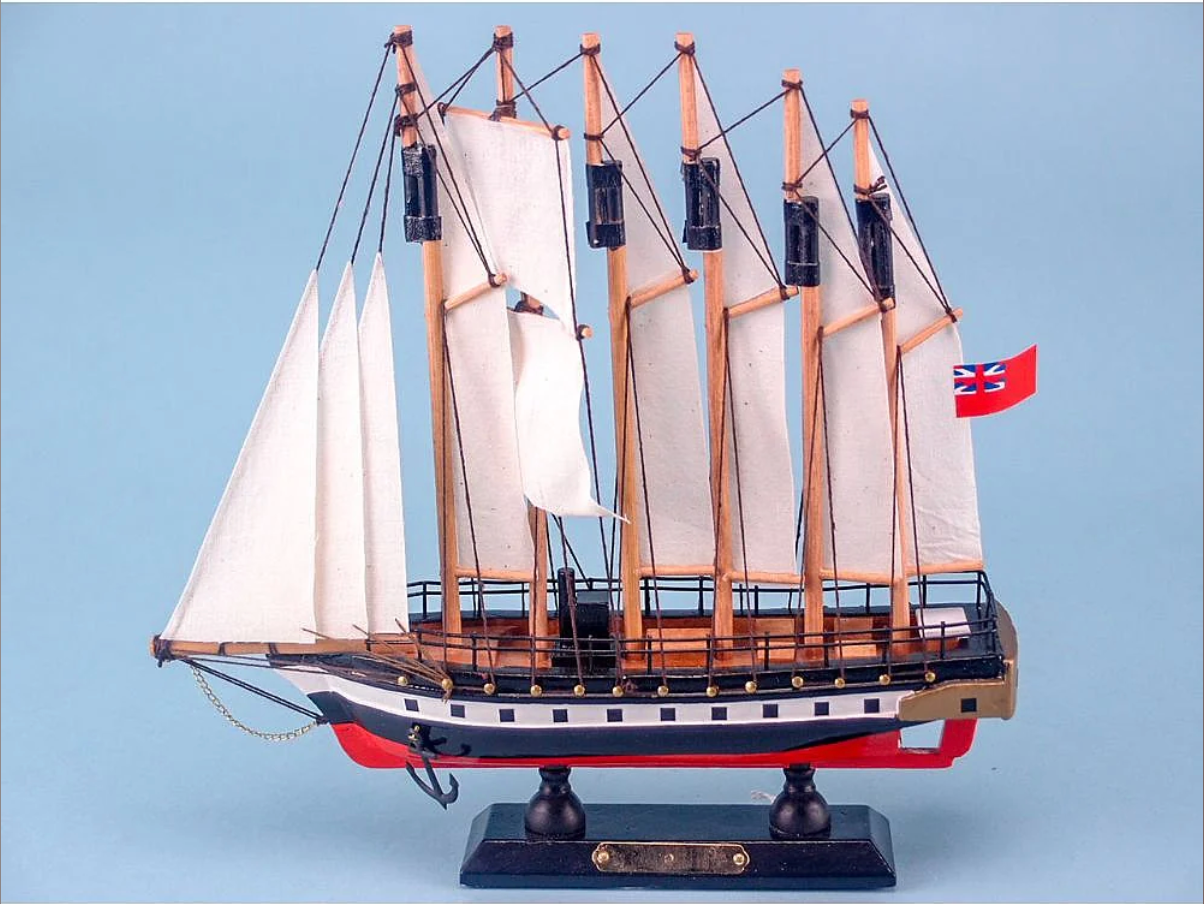 Model sailboat with white sails and a British flag on a light blue background