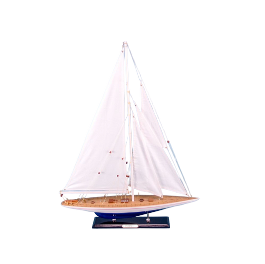 Model sailboat with white sails on a light blue background